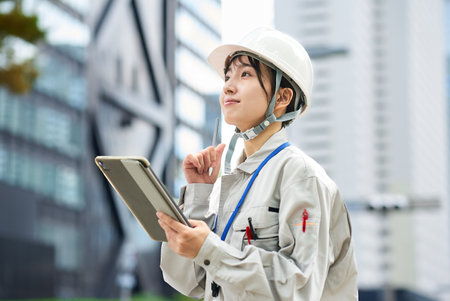A young woman wearing work clothes and a helmet outdoorsの写真素材