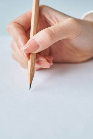 Hand holding a pencil and blank paper on studioの写真素材