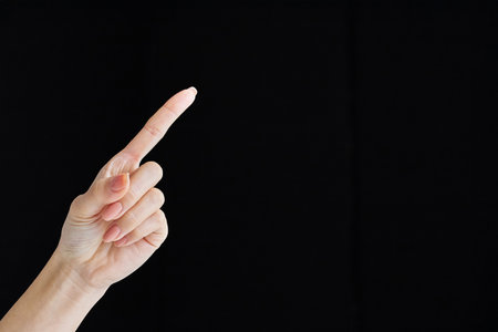 Pointing with index finger at studio of black backgroundの写真素材
