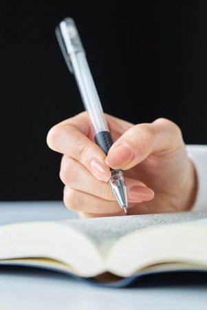 Hands of a person studying with a text and pen