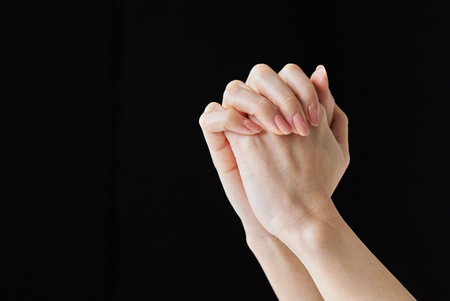 Both hands with interlocking fingers and black backgroundの写真素材