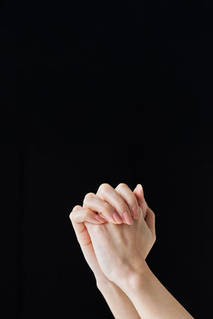 Both hands with interlocking fingers and black backgroundの写真素材