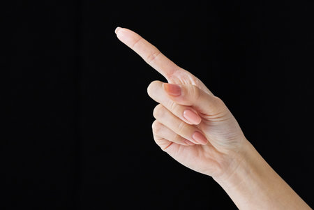 Pointing with index finger at studio of black backgroundの写真素材