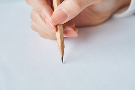 Hand holding a pencil and blank paper on studioの写真素材