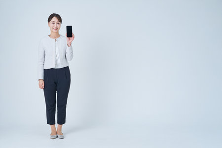 A woman operating a smartphone and white backgroundの写真素材