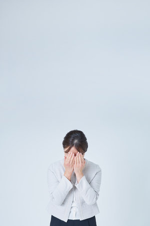 Woman covering her face with both hands and white backgroundの写真素材
