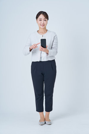 A woman operating a smartphone and white backgroundの写真素材