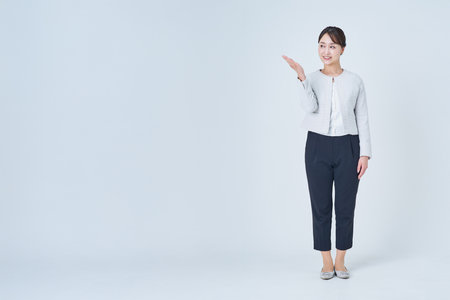 A businesswoman posing to guide or point out and white backgroundの写真素材