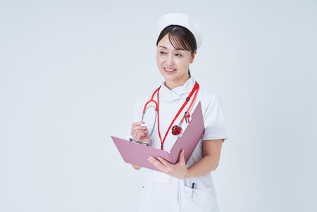 A female medical staff member holding a document and taking a medical examinationの写真素材