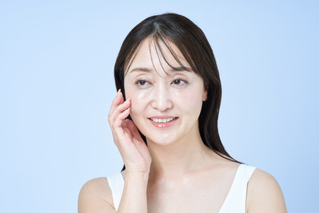Middle aged woman touching her skin and white backgroundの写真素材