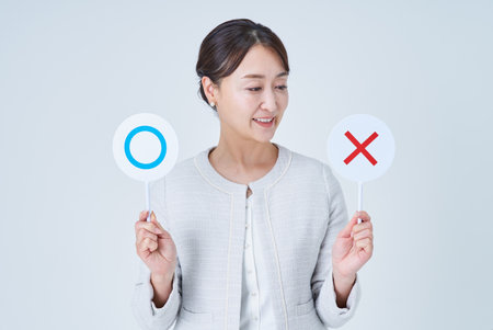 Businesswoman holding a plate with a circle and a cross and white backgroundの写真素材
