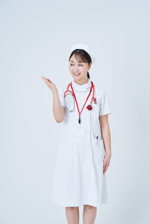 A female medical staff member posing as a guide and white backgroundの写真素材