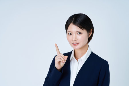 Young business woman pointing up and white backgroundの写真素材