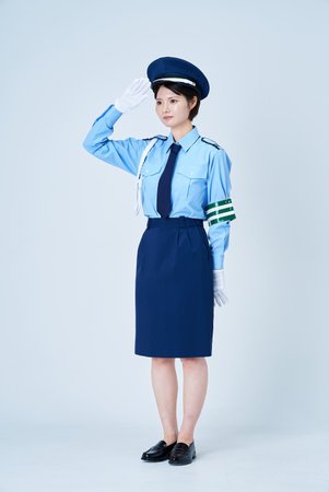 A woman in a security guard uniform saluting and white backgroundの写真素材