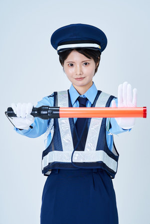 A woman wearing a security guard uniform and holding a red stick and white background