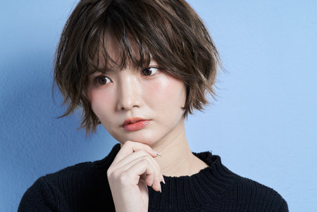 A young woman with short hair and a worried expressionの写真素材