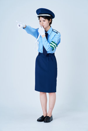 A female security guard blowing a whistle and pointing on a white background