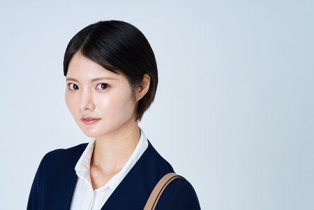 A young woman in a suit commuting to work and white backgroundの写真素材