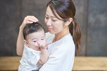 A smiling mother holding her baby indoorsの写真素材