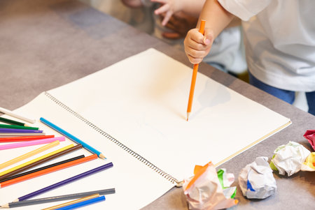 A child drawing with colored pencils in the living roomの写真素材