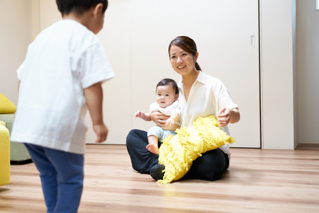 Mother and children playing happily in the roomの写真素材