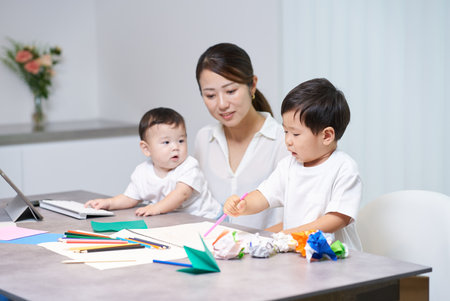 A child playing next to his mother who is working remotely in a roomの写真素材