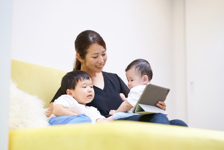 Mother and child sitting on sofa looking at tablet screen