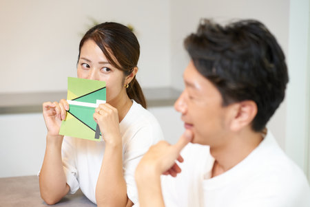 A woman holding a bankbook and looking suspiciously at a manの写真素材