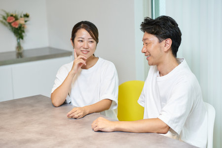 A man and a woman smiling and talking in the living roomの写真素材