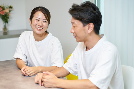 A man and a woman smiling and talking in the living roomの写真素材