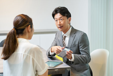 A man in a suit talking to a woman indoorsの写真素材