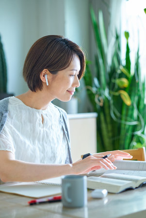A woman studying in her room with earphones