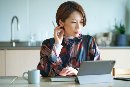 Middle-aged woman working in the living roomの写真素材