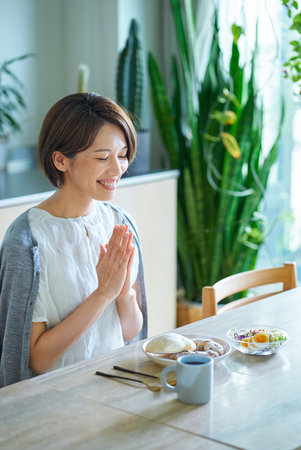 A middle-aged woman eating breakfast in her roomの写真素材