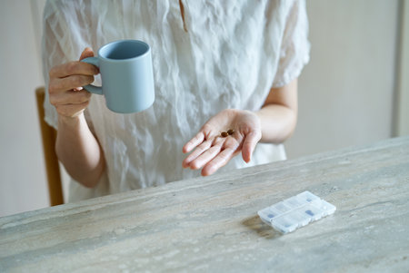 A middle-aged woman taking supplements in her roomの写真素材