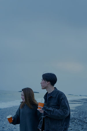 Young man and woman walking on the beach just after sunsetの写真素材