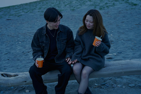 Young man and woman walking on the beach just after sunsetの写真素材