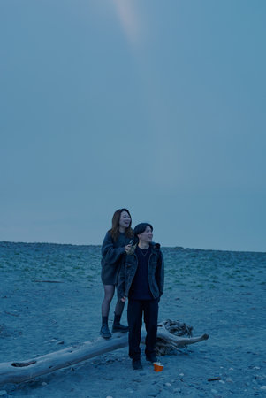 Young man and woman walking on the beach just after sunset