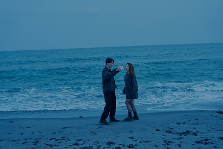 Young man and woman walking on the beach just after sunsetの写真素材