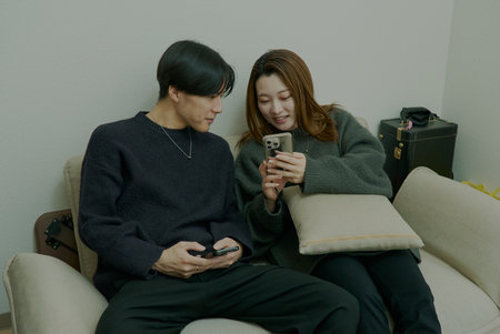 Young lovers watching and operating smartphone in a roomの写真素材