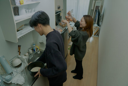Young man and woman cooking together in the roomの写真素材