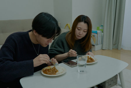 Young man and woman eating curry rice in a roomの写真素材