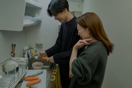 Young man and woman cooking together in the roomの写真素材