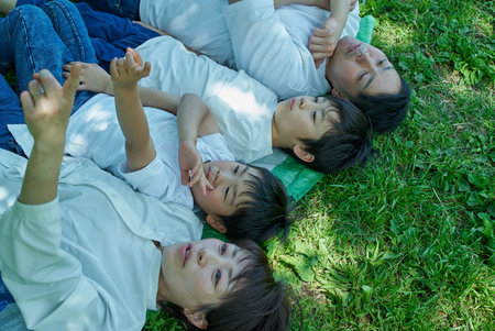 A family of four relaxing and snuggling together in a green space on a sunny day