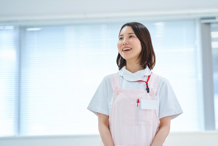 A woman in a white coat and apron in a roomの写真素材