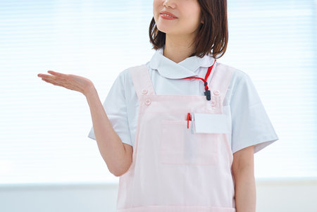 A woman in a white coat and apron in a roomの写真素材