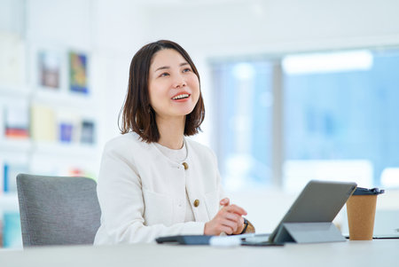 A young woman talking to a colleague at workの写真素材