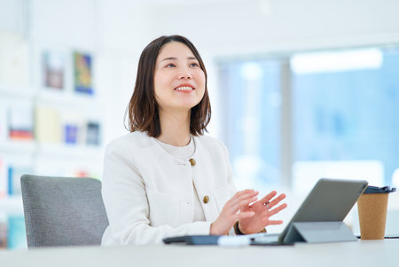 A young woman talking to a colleague at workの写真素材