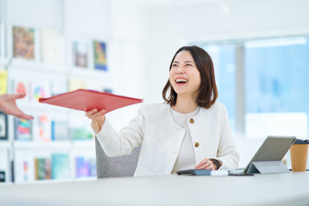 A young woman talking to a colleague at workの写真素材