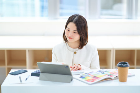 A young woman in a suit working indoorsの写真素材